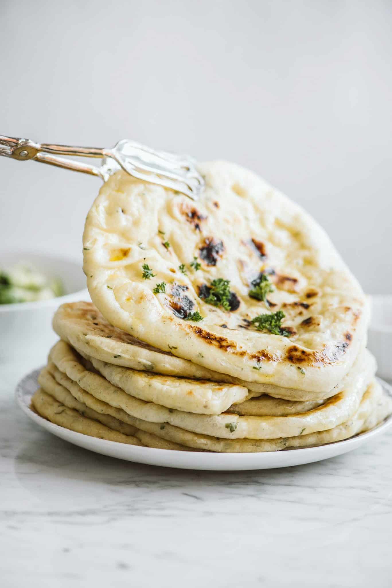 plate of stacked pita bread garnished with herbs on a white plate