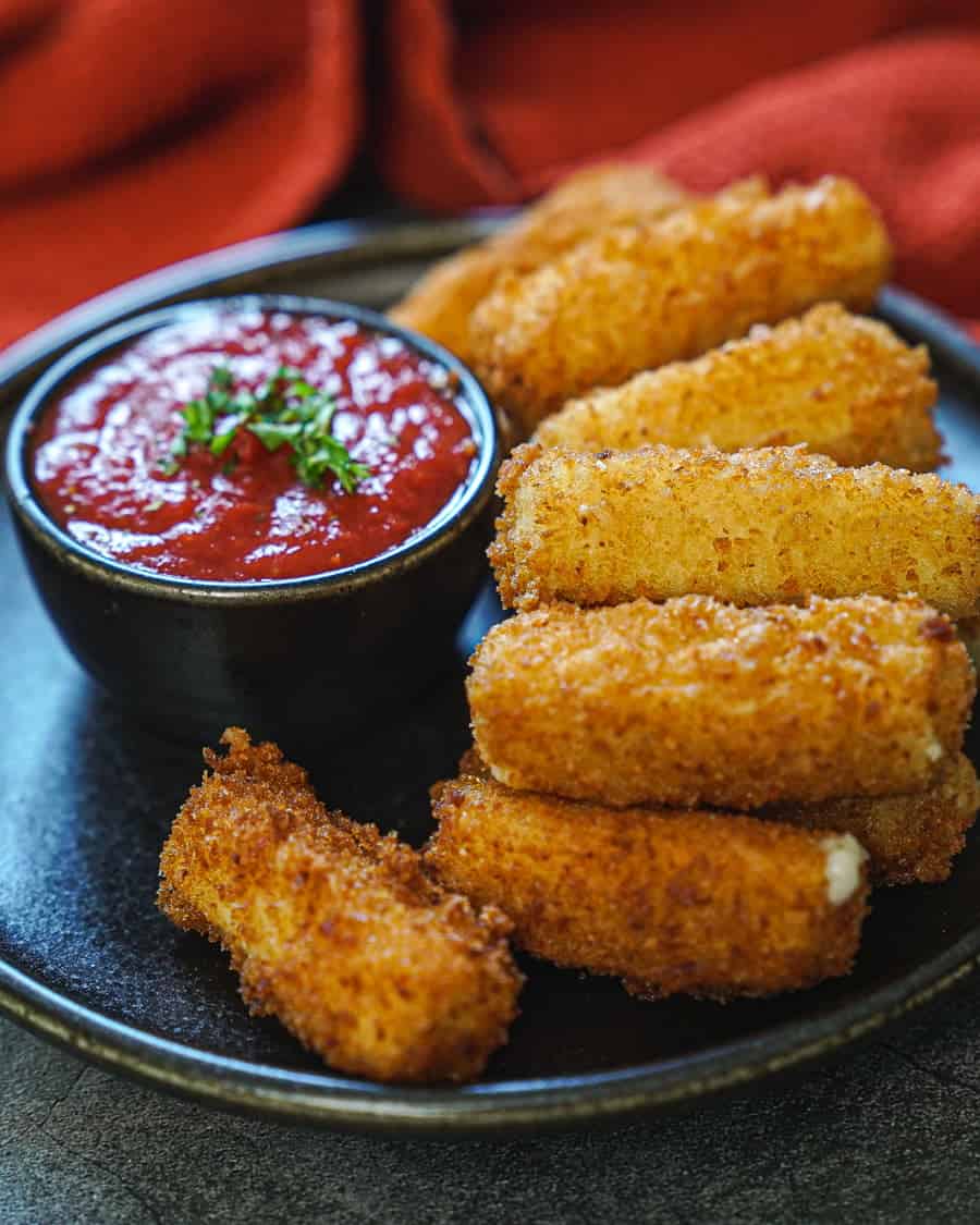 vegan mozzarella sticks on a plate with red marinara in a bowl