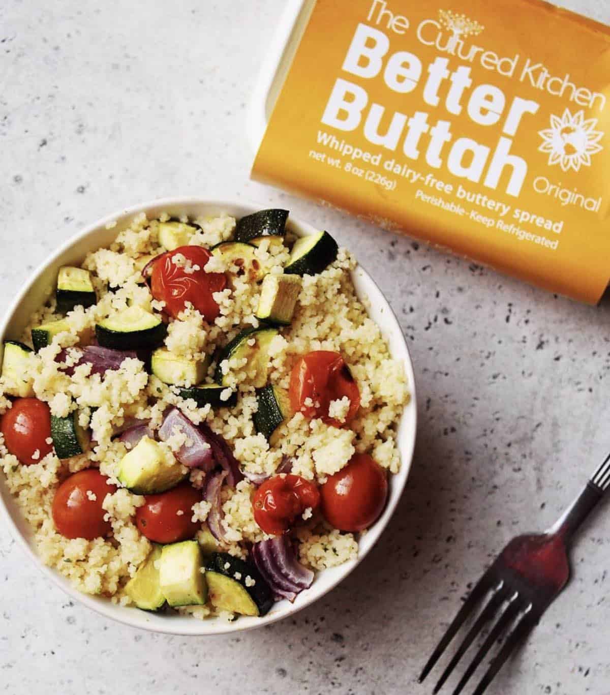 Bowl of vegan tofu scramble next to a package of dairy-free better buttah from The Cultured Kitchen.
