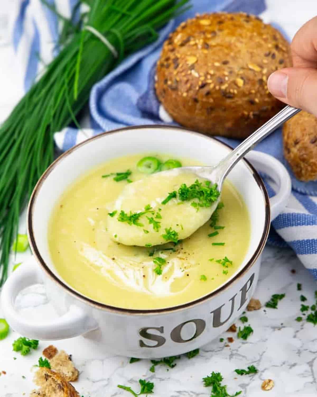 A bowl of vegan cauliflower soup with a spoon scooping some up.