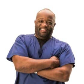 Photo of plant-based doctor Milton Mills wearing a blue scrub outfit.