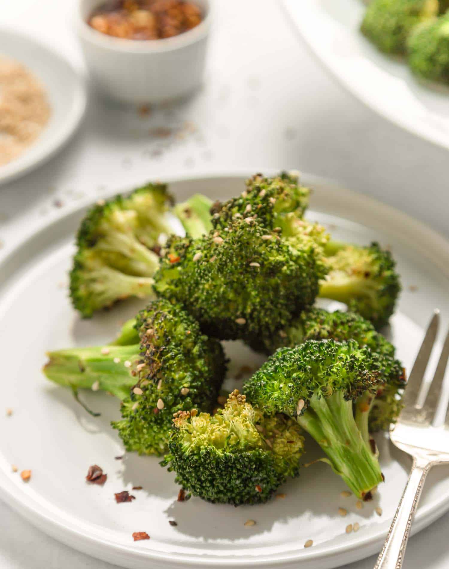 air fried broccoli on a white plate with a fork on the side