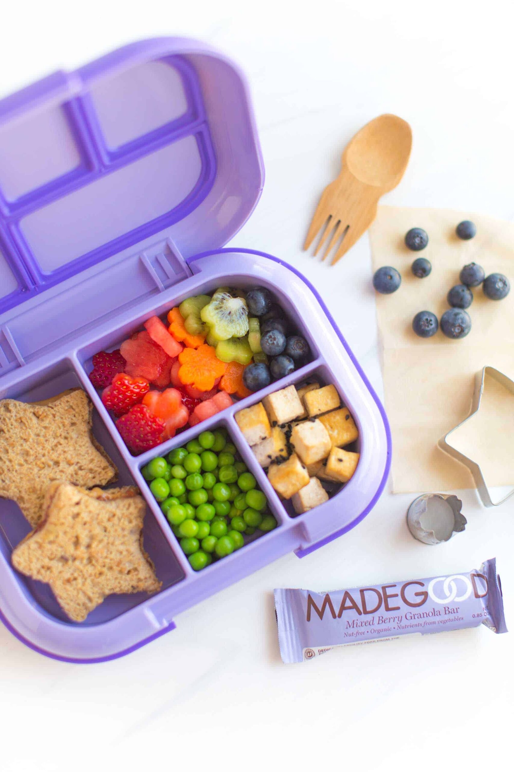 Kids lunch box packed with tofu, peanut butter and jelly, fruit, peas, and a MadeGood snack bar. 
