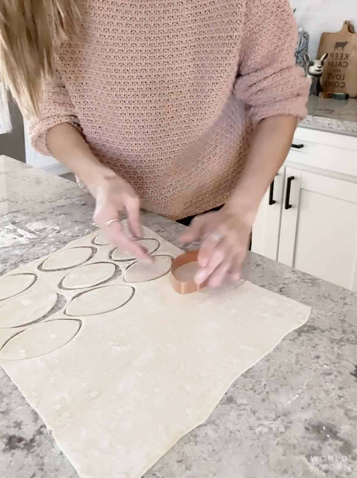 Cutting football cookie cutter shapes out of pastry dough.