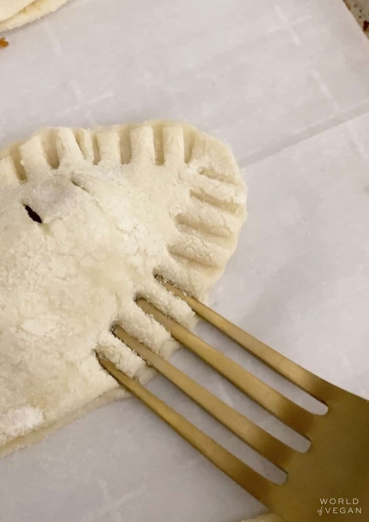 Pressing dough together with a gold fork.