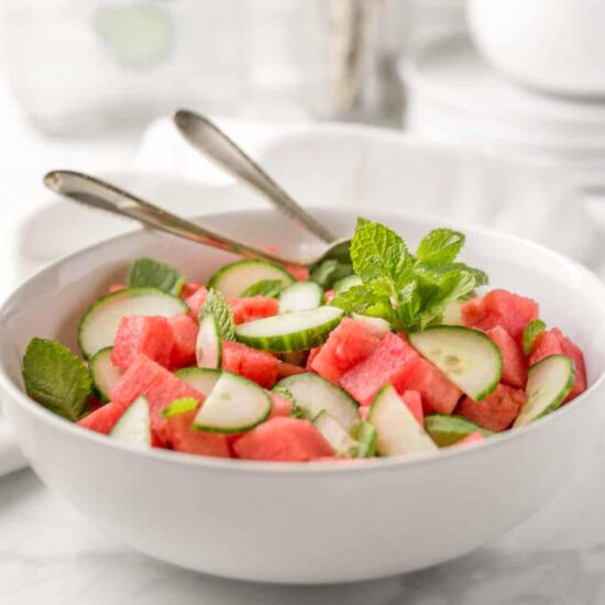 Watermelon Cucumber Fruit Salad Photo In a White Bowl With Serving Utencils