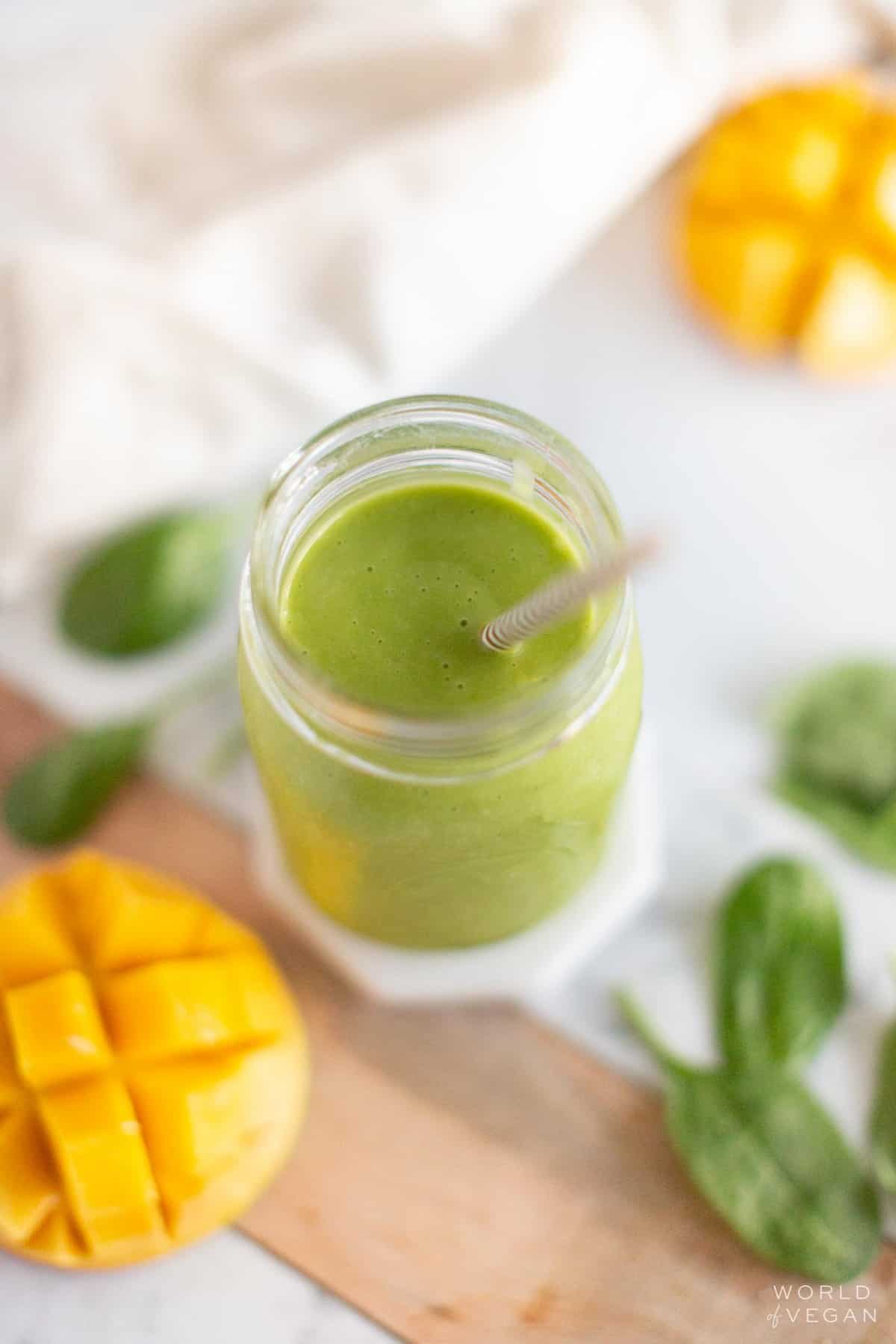 A top-down, angled shot of a mango spinach smoothie.