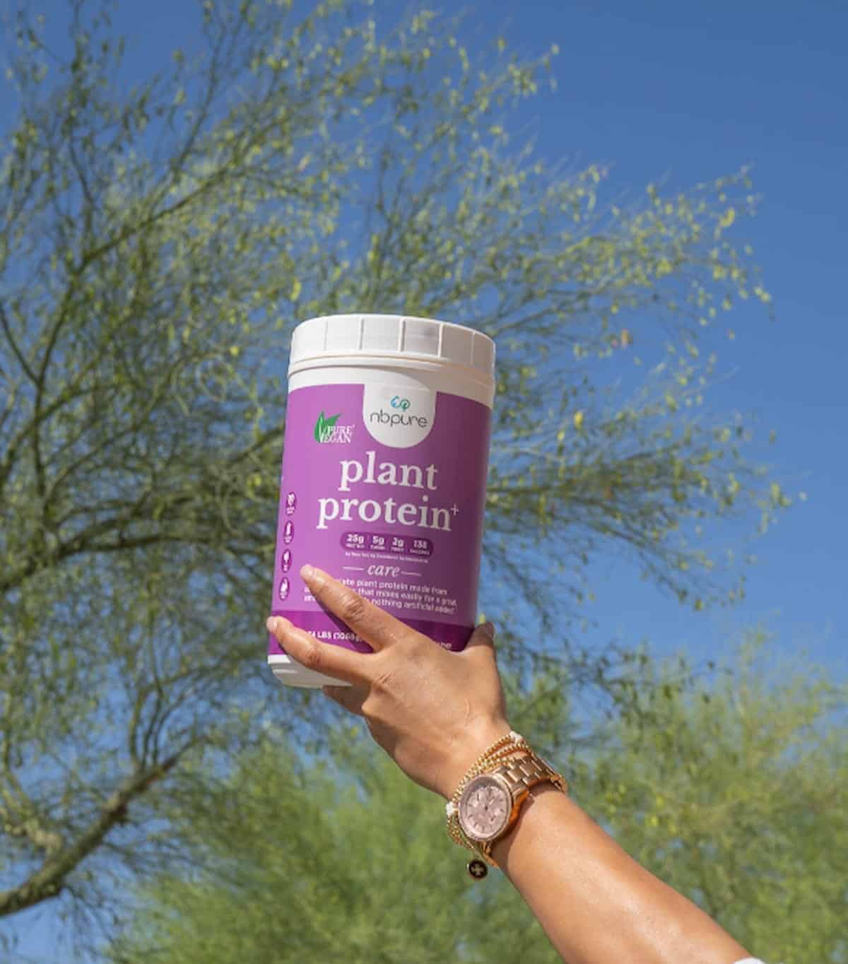 A hand holding up a package of NB Pure's plant protein.