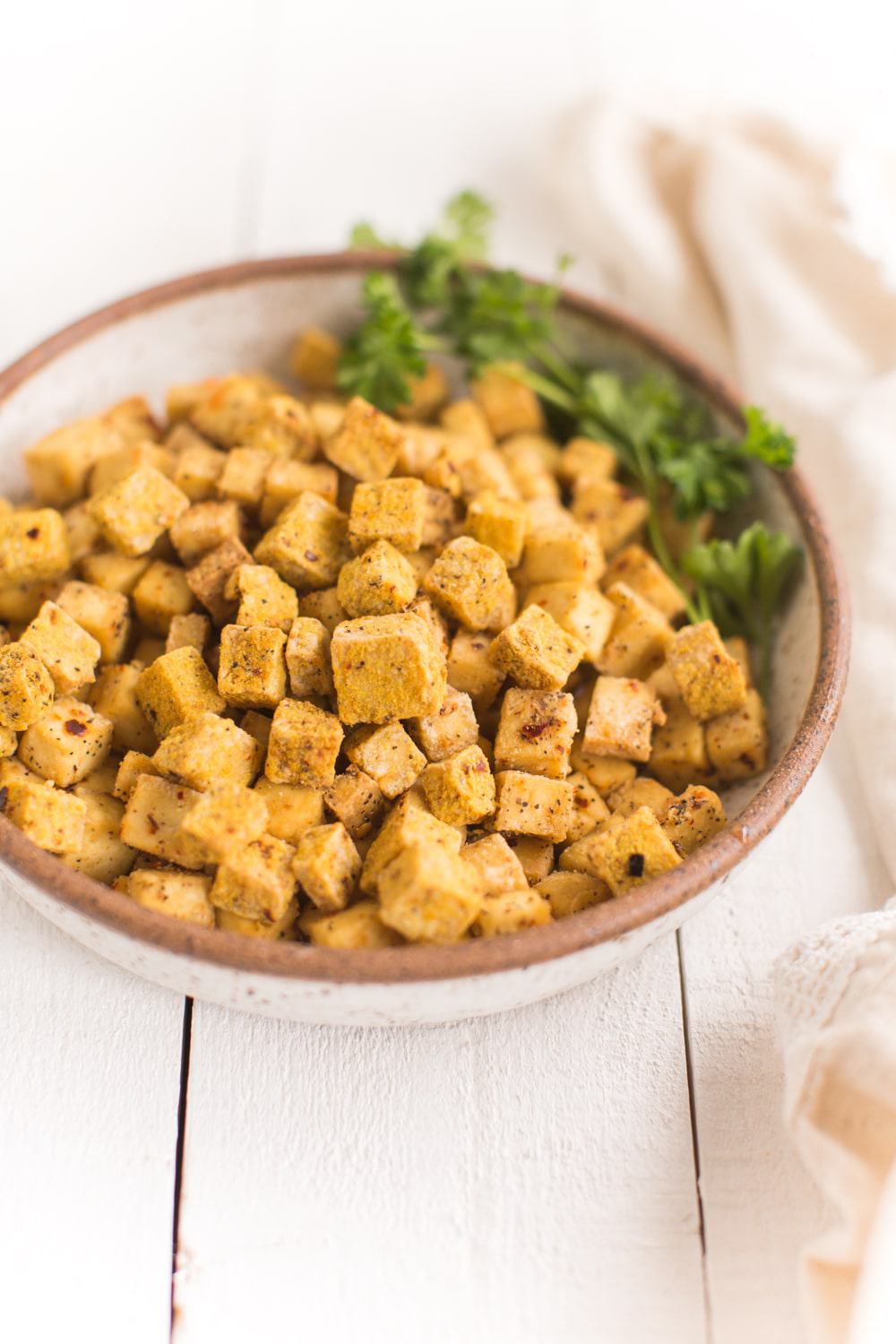 air fried tofu cubes in a bowl with parsley garnish