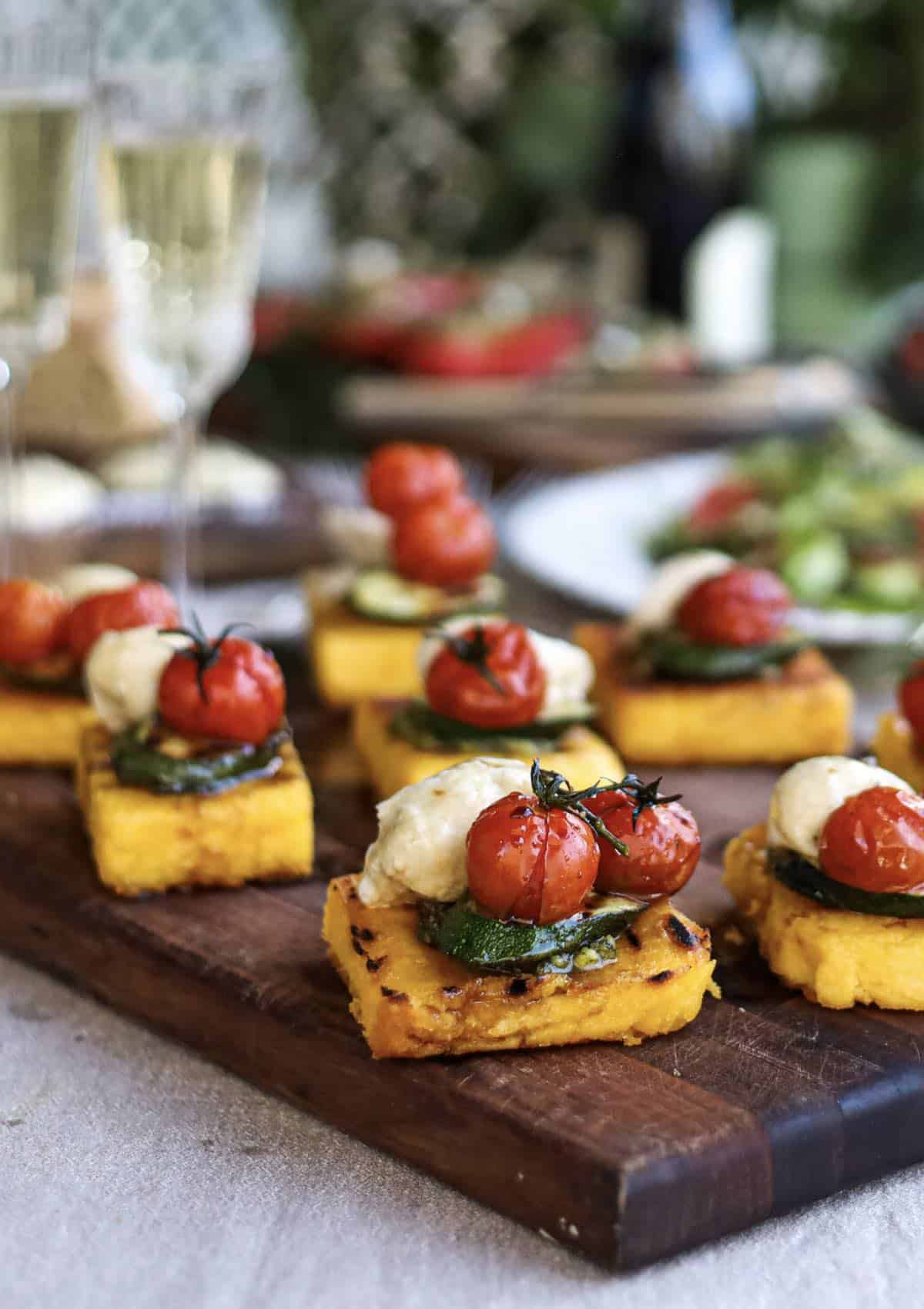 Appetizers made from polenta squares topped with zucchini and tomato. 