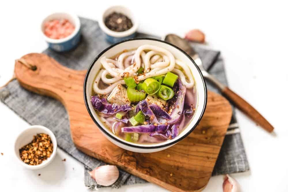 Vegetarian Udon Soup in a Bowl on a Wood Cutting Board
