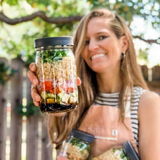 Vegan holding up a jar of the quinoa salad.