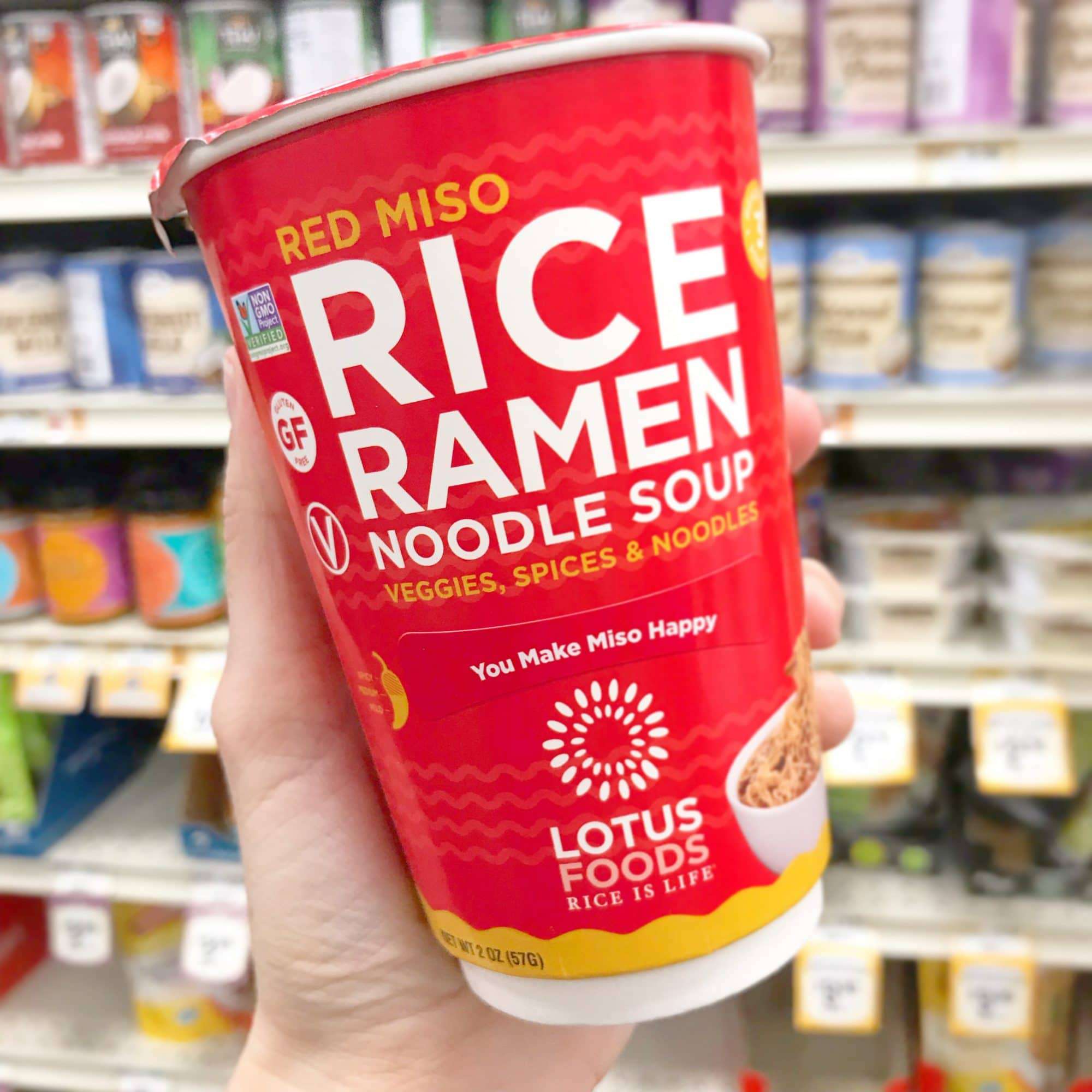 A hand holding a cup of instant Rice Ramen Noodle Soup from Lotus Foods.