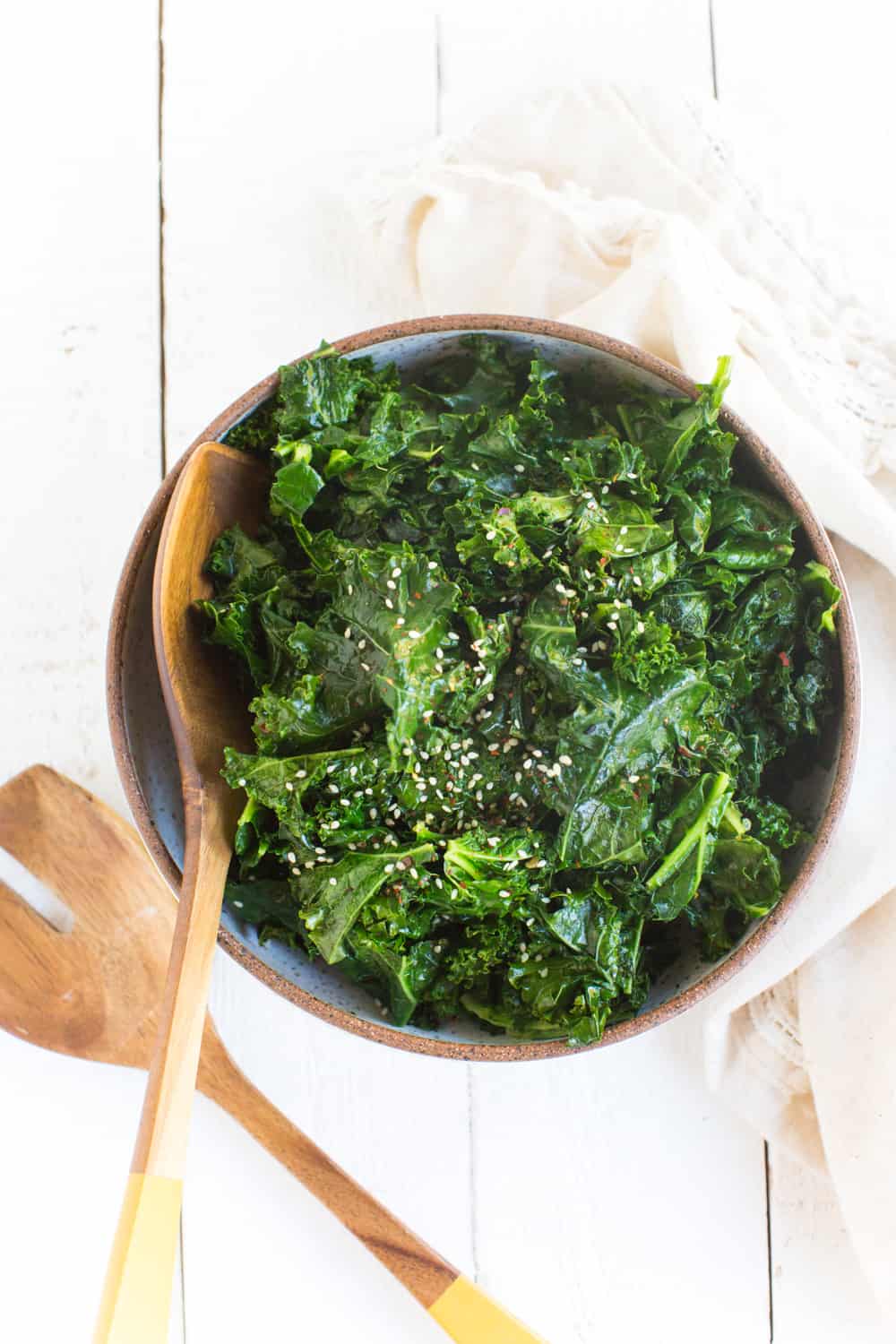 Bowl of Kale with Sesame with wooden serving spoons