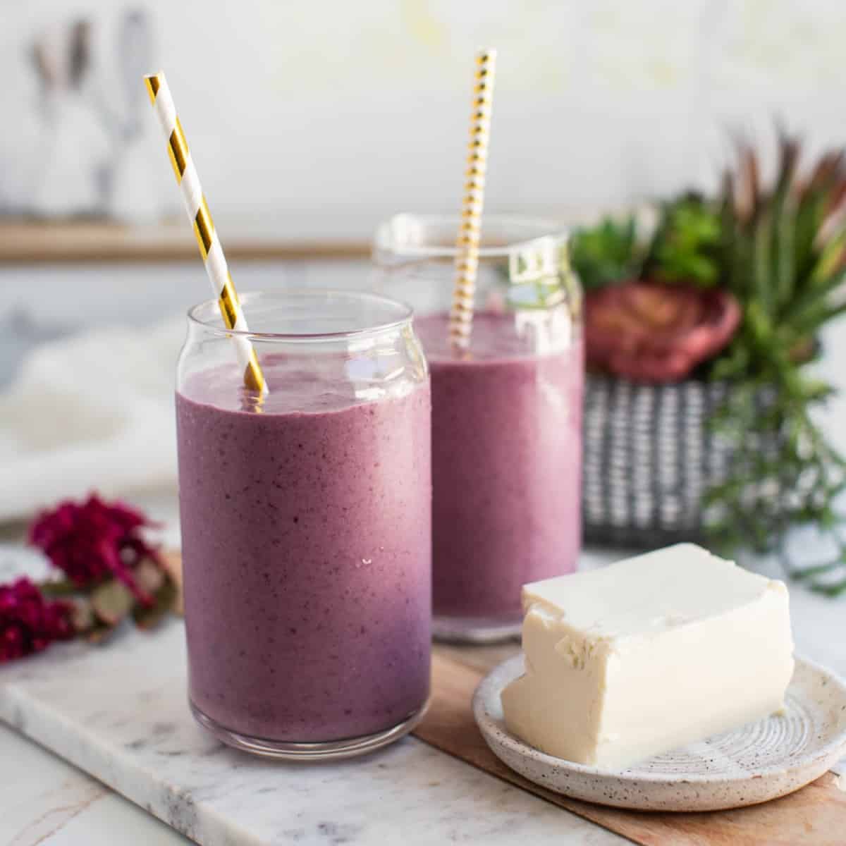 Two cups of purple cherry smoothie made with silken tofu with a block of open silken tofu next to them.