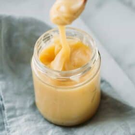 vegan condensed milk in a jar with a spoon dropping some to show consistency