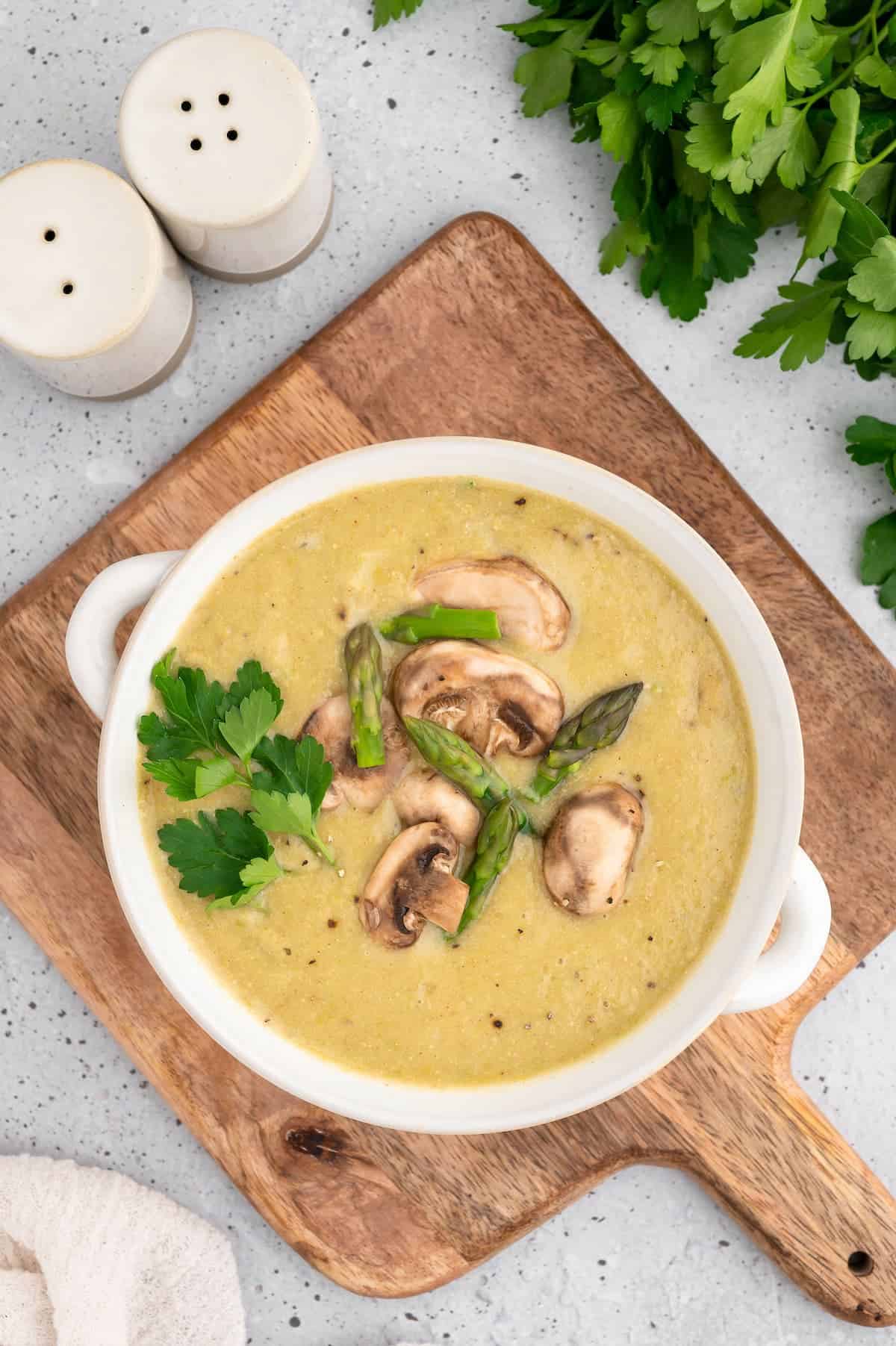 A bowl of vegan asparagus soup on a wooden board.