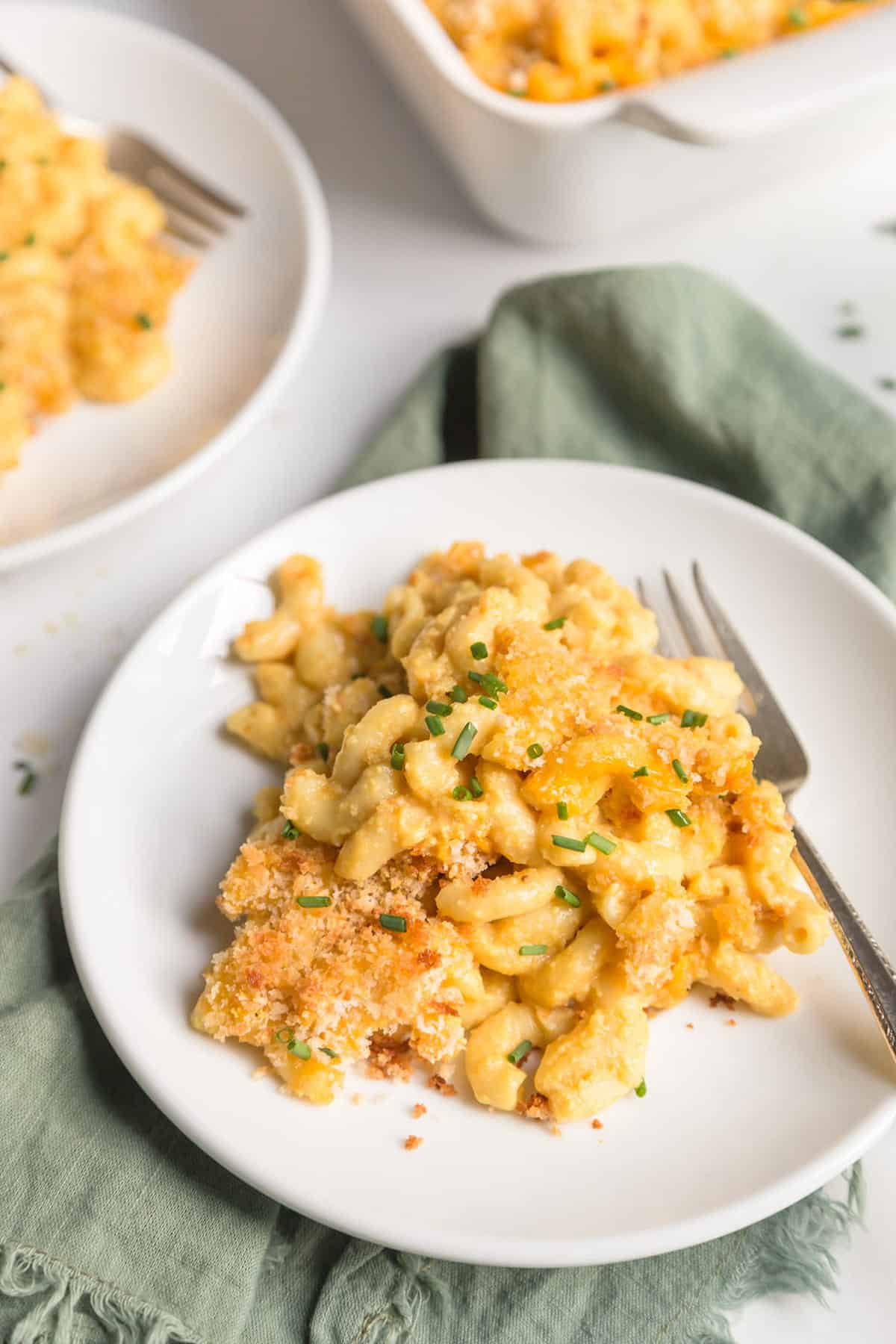 Vegan baked mac and cheese on a white serving plate with a fork.