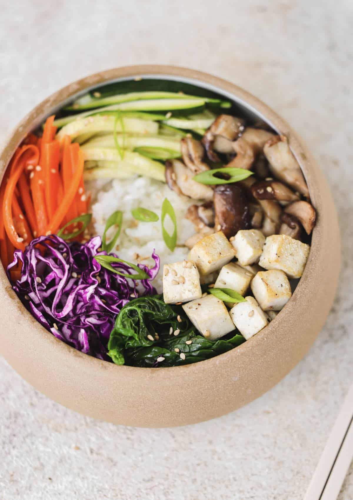 Vegan Korean Bibimbap bowl with fresh veggies and tofu. 