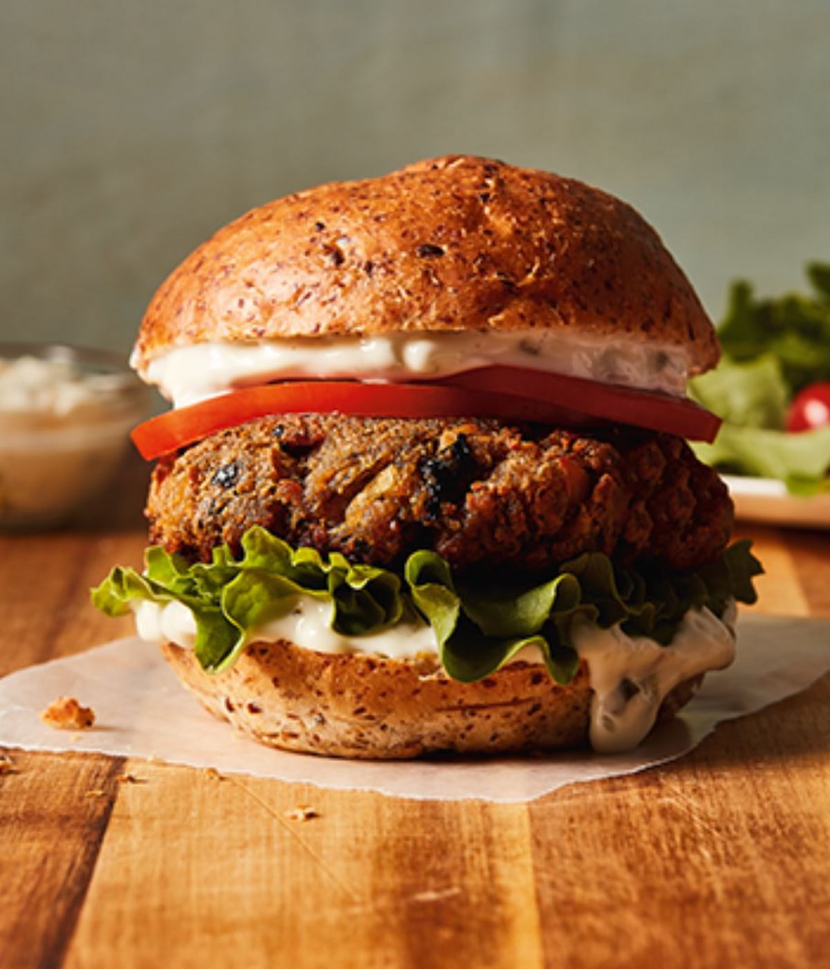 A vegan burger with sauce, tomato, and lettuce.