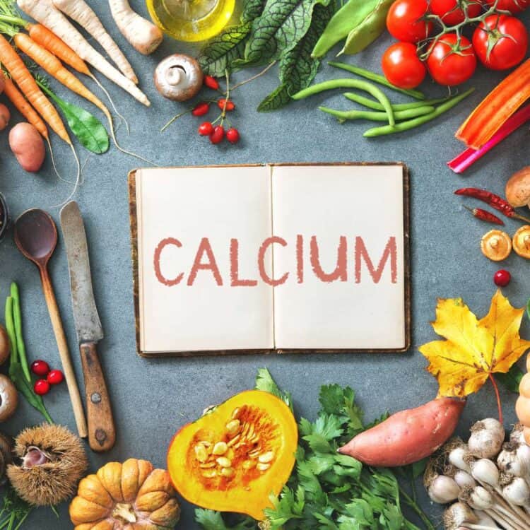 Table filled with plant-based vegan foods with a notebook with the word "calcium" on it.