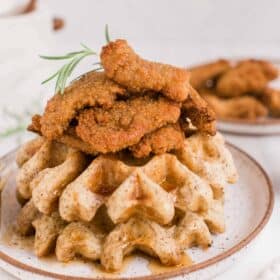 Vegan Chicken and Waffles Stacked on a Plate Topped With Air Fried Nowadays Nuggets and Maple Syrup