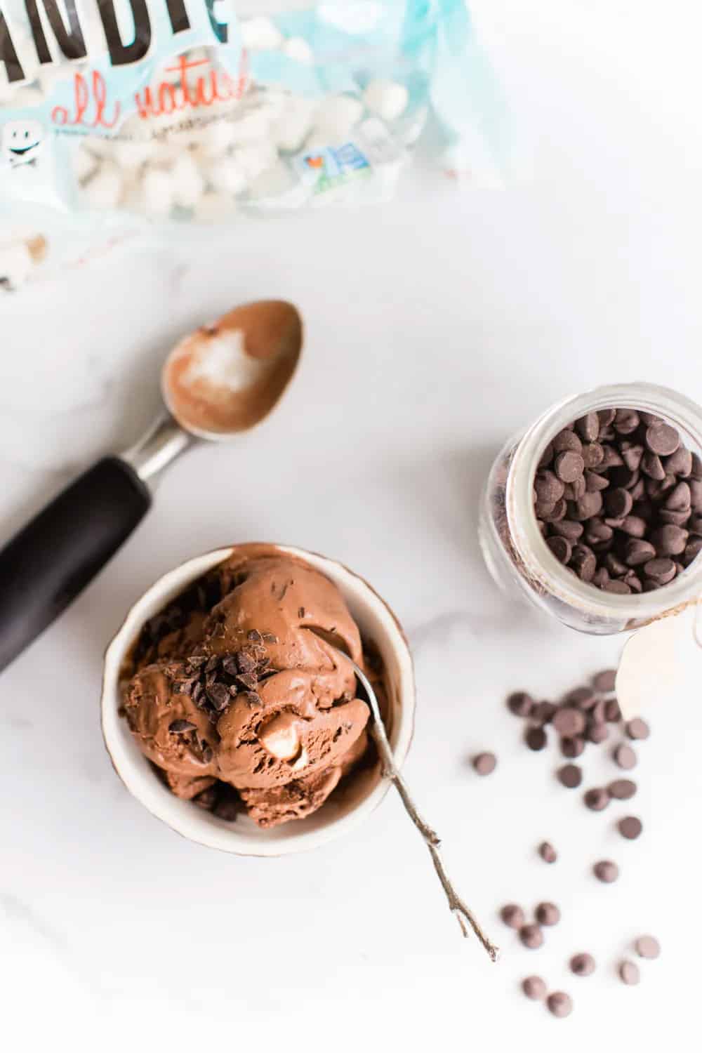 vegan rocky road ice cream in a bowl with chocolate chips on the right and an ice cream scoop on the left for aesthetic