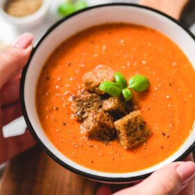 Vegan Creamy Tomato Soup in a Bowl on a Wood Cutting Board