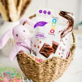 Straw easter basket with a purple stuffed beanie baby bunny and OCHO vegan chocolate caramel candies.
