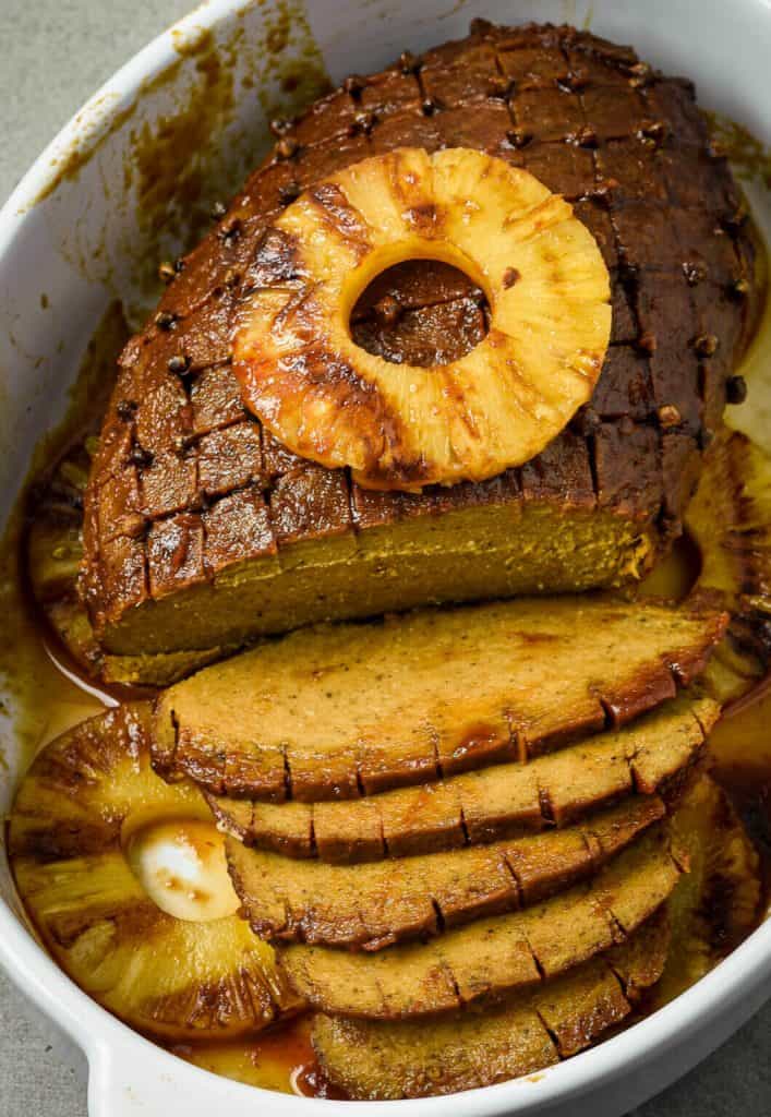 roasted vegan ham partially sliced with a grilled pineapple circle on top