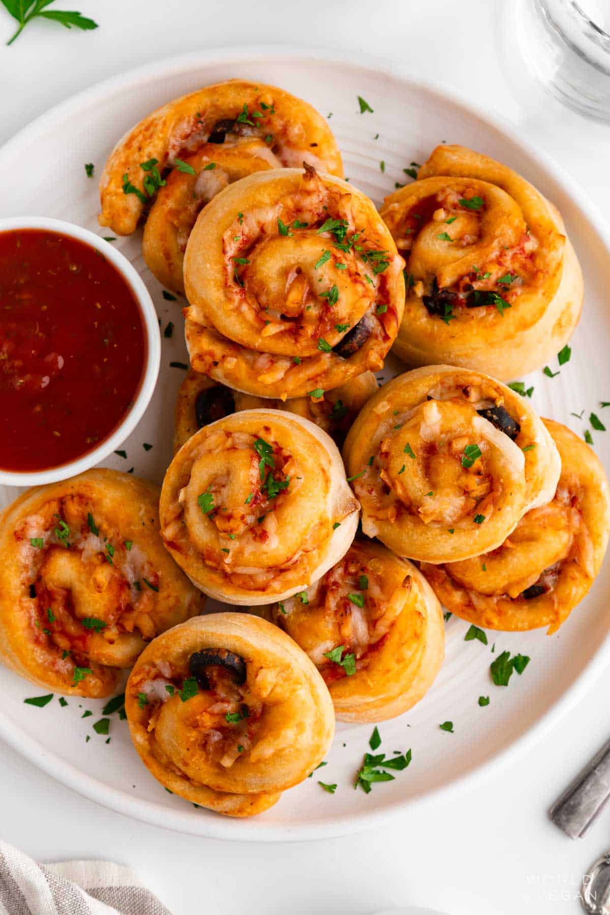 A plate of vegan pizza rolls served with marinara sauce.