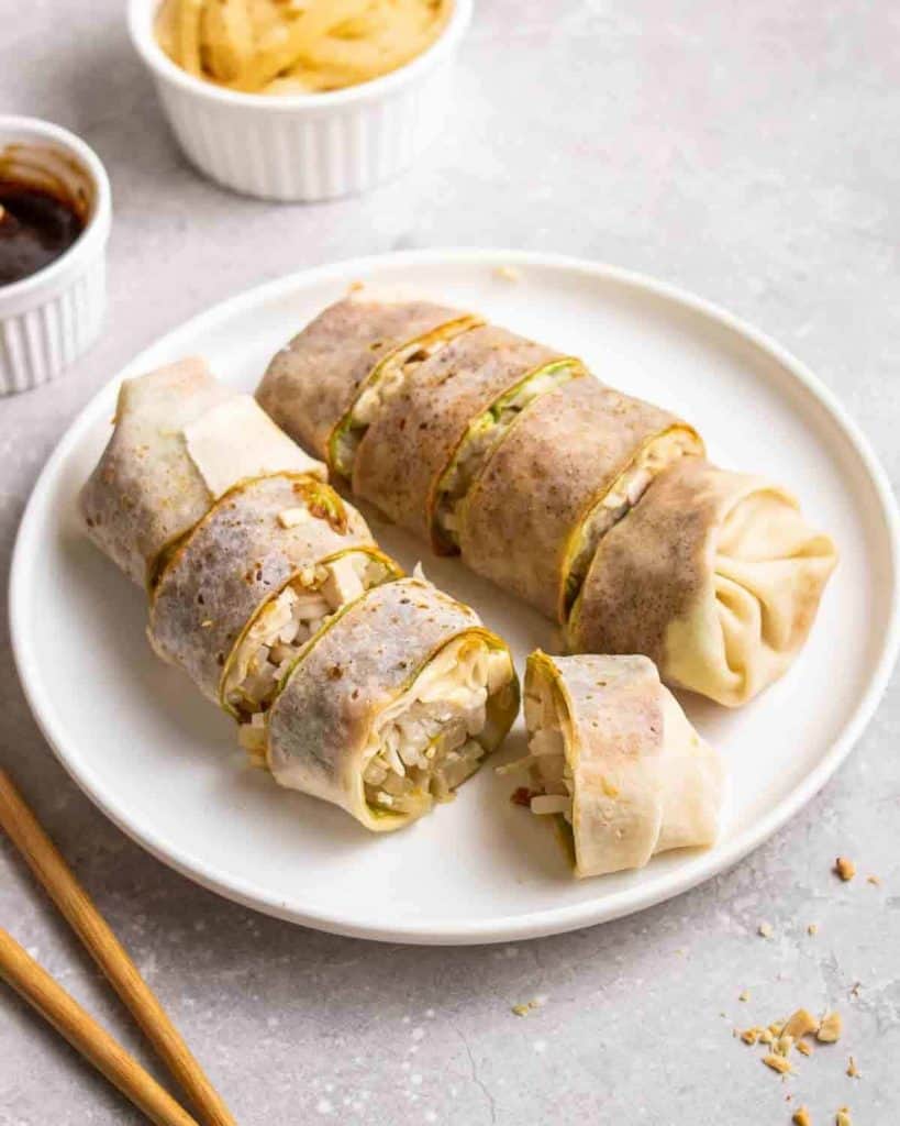 vegan malaysian spring rolls on a white plate filled with tofu, bean sprouts, jicama, lettuce, and hoisin sauce