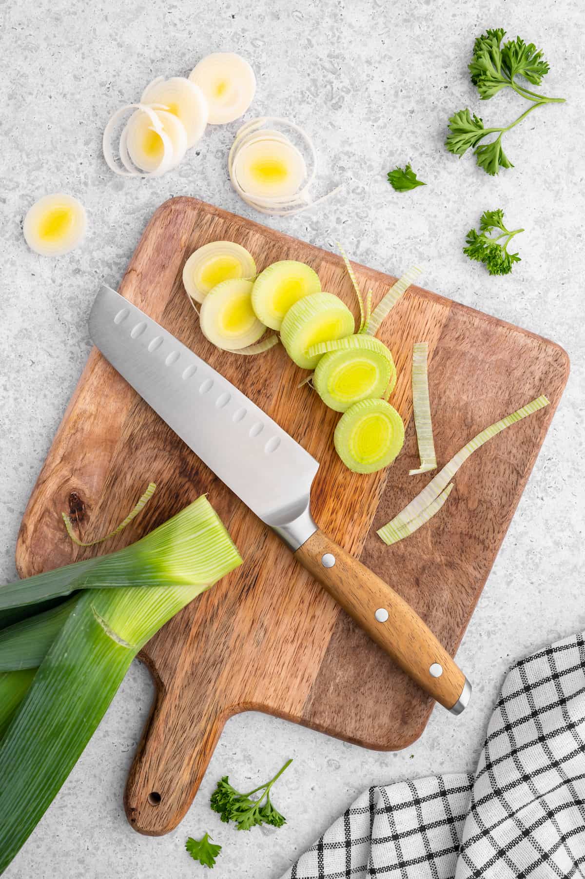 Chef's knife on a cutting board with vegetable ingredients. 
