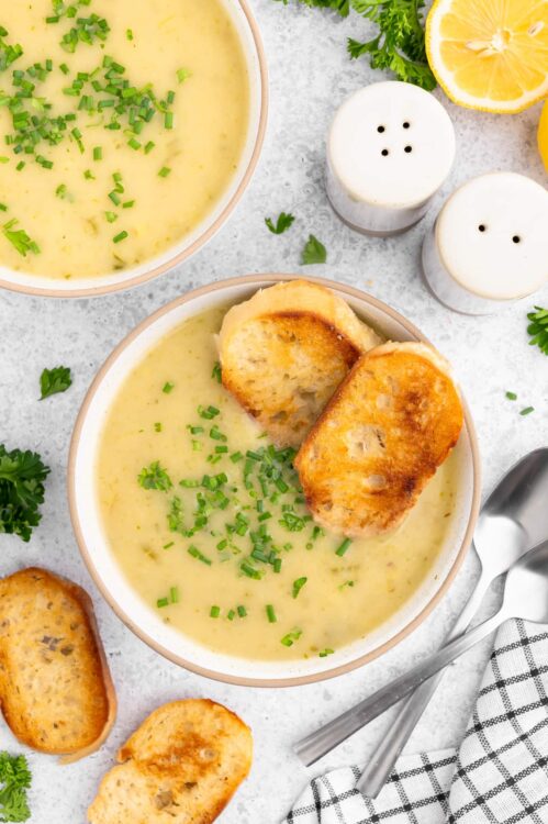 Creamy potato soup with slices of bread and topped with herbs.