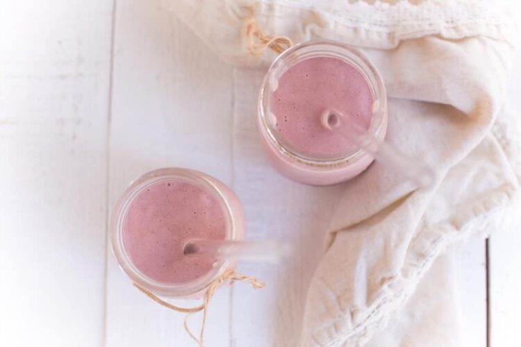 Two Mason Jars filled with Strawberries and Cream Smoothie and a cream colored cloth