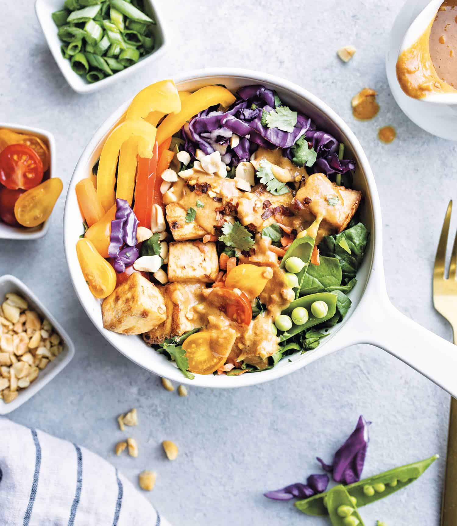 Colorful tofu Thai salad in a bowl topped with nuts and fresh cilantro.