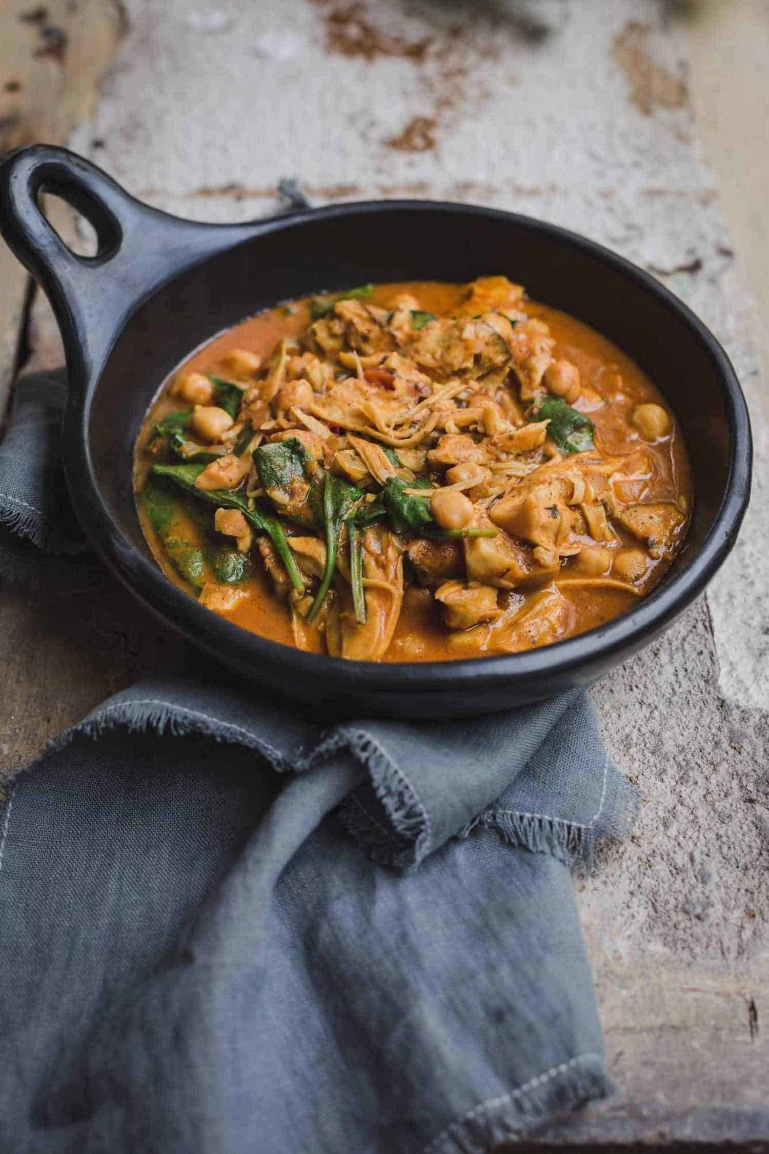 vegan tikka masala on a cast iron skillet with spinach, chickpeas, and mushrooms