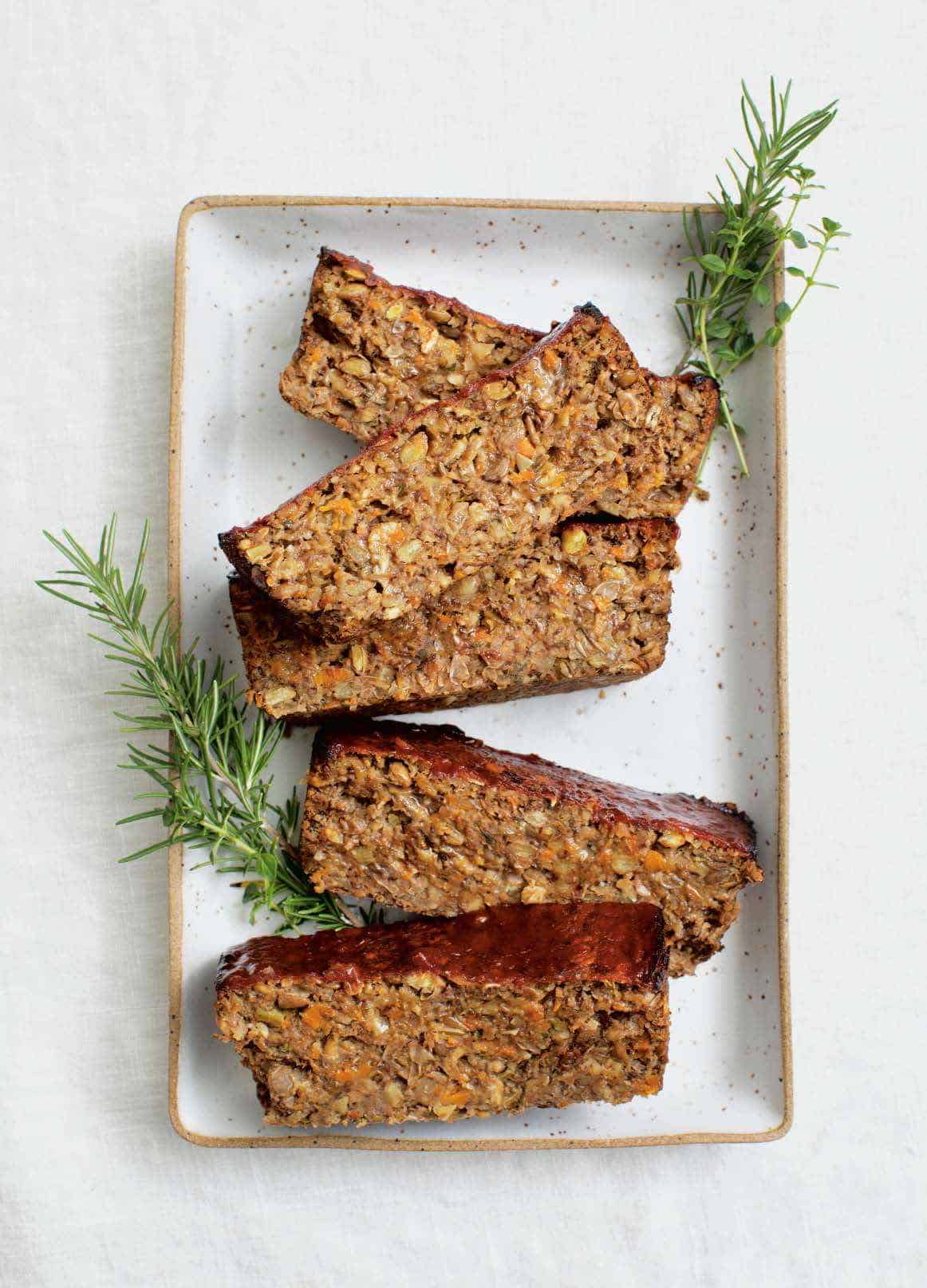 veggie lentil loaf served on a white plate with rosemary