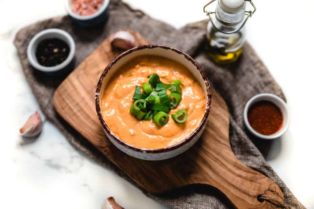 Bowl of Vegan Buffalo Queso Sauce on a Wooden Board